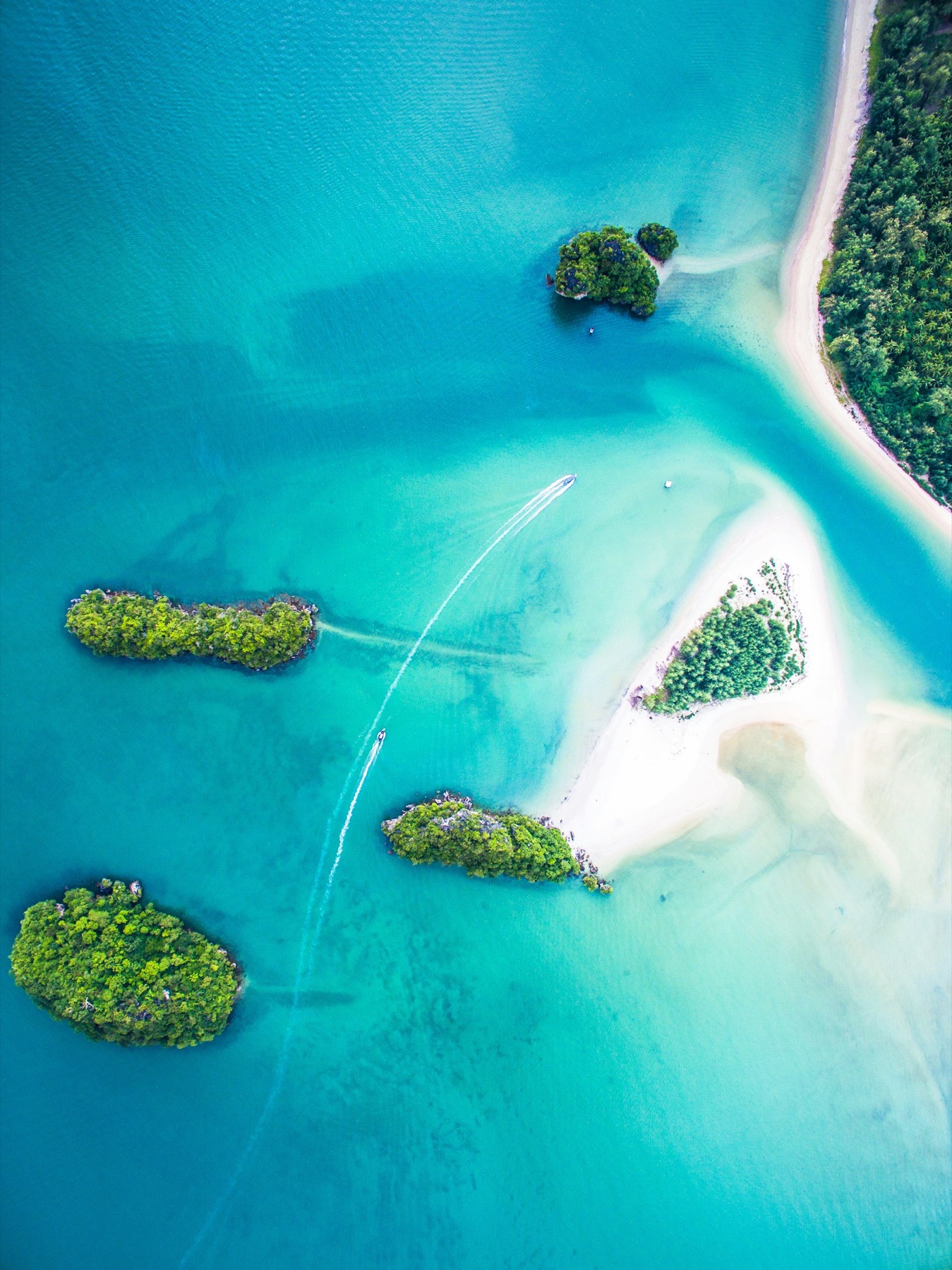 Aerial view of jungle islets and sandbars in turquoise water — the Riau archipelago off Bintan.