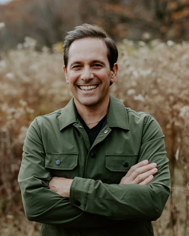 Francesco D’Avola — a smiling man in an olive-green jacket, arms crossed, in an autumn field.