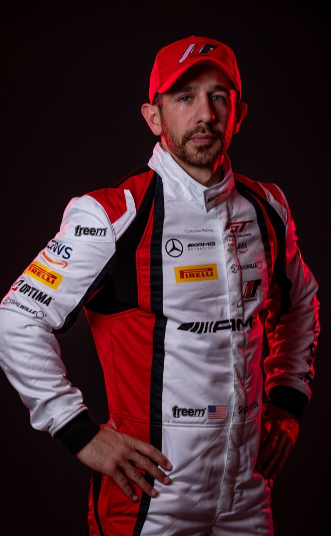 Michai Stephens — a bearded racing driver in a red cap and white-and-red race suit.